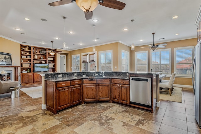 kitchen with a warm lit fireplace, a sink, ornamental molding, stainless steel appliances, and brown cabinets