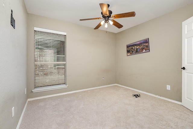 carpeted empty room featuring baseboards and a ceiling fan