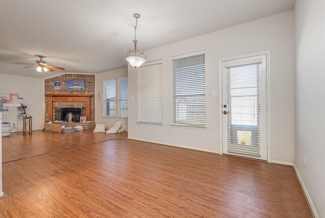 unfurnished living room featuring a ceiling fan, wood finished floors, a fireplace, and vaulted ceiling