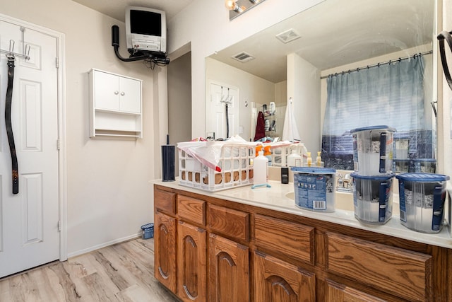 bathroom with visible vents, vanity, baseboards, and wood finished floors