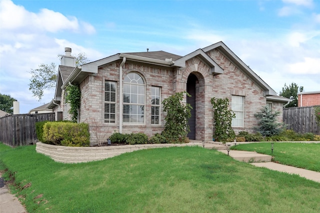 view of front of property featuring brick siding, a front lawn, and fence