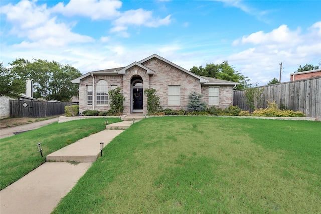 view of front of home with brick siding, a front yard, and fence