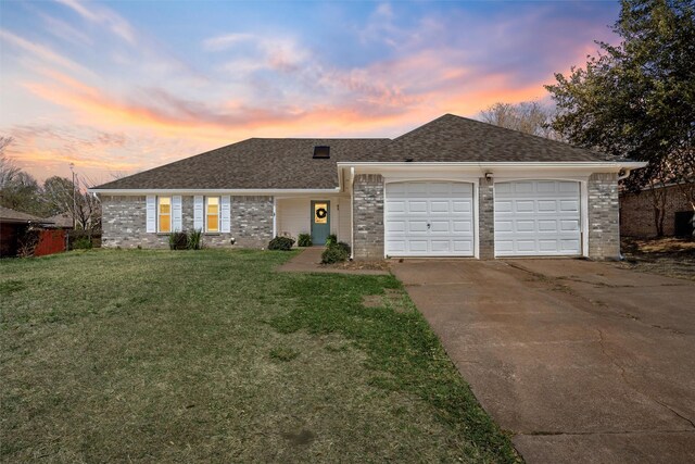 view of front of house featuring a front yard, roof with shingles, concrete driveway, a garage, and brick siding