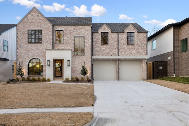 view of front of property featuring a garage, brick siding, driveway, and roof with shingles