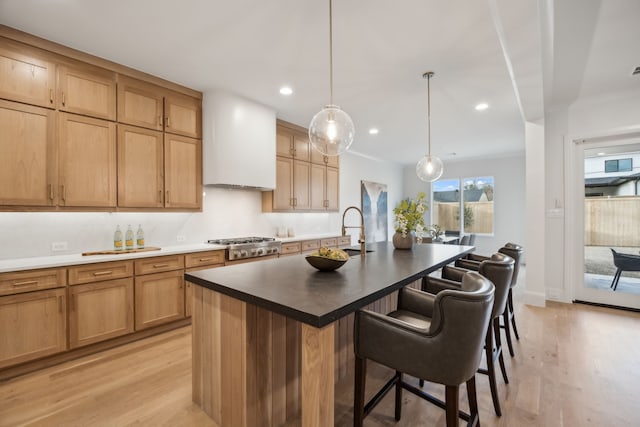 kitchen featuring a kitchen bar, a center island with sink, recessed lighting, light wood-style floors, and custom exhaust hood