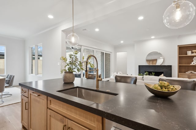 kitchen with recessed lighting, a fireplace, light wood-type flooring, and a sink