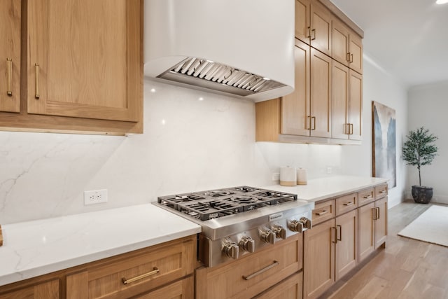 kitchen featuring custom exhaust hood, light stone counters, light wood-style floors, and stainless steel gas stovetop