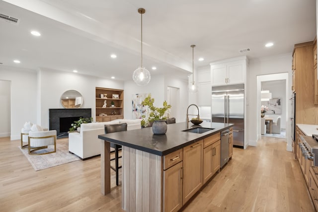 kitchen featuring visible vents, a breakfast bar, a sink, stainless steel appliances, and a premium fireplace