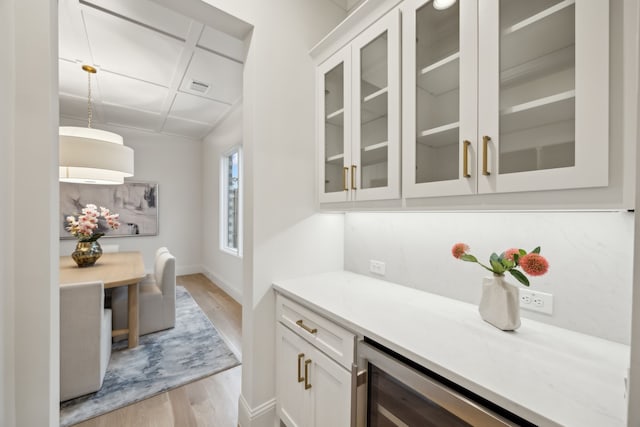 bar with visible vents, baseboards, light wood-style flooring, and hanging light fixtures