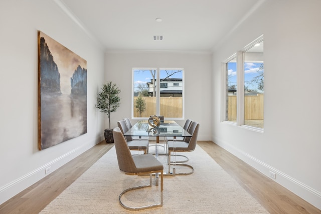 dining area featuring visible vents, light wood-type flooring, baseboards, and ornamental molding