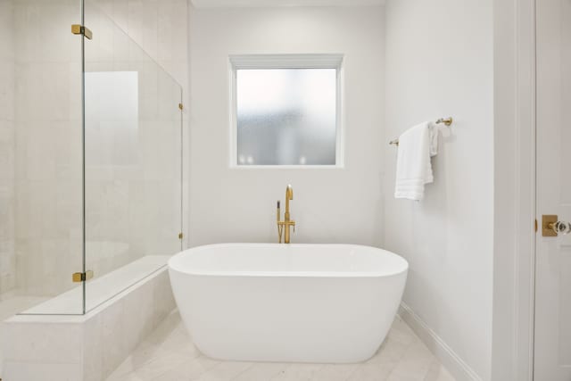 full bathroom featuring a soaking tub, a stall shower, and baseboards