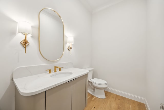 bathroom featuring toilet, vanity, baseboards, and wood finished floors