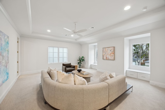 living area featuring a raised ceiling, light carpet, and a healthy amount of sunlight