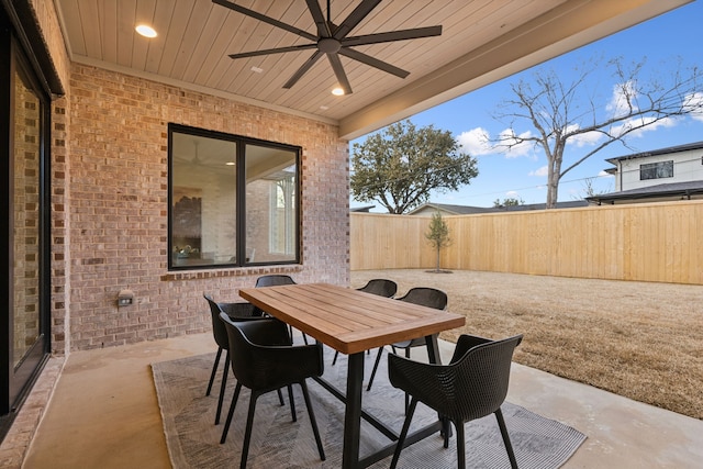 view of patio featuring outdoor dining area, ceiling fan, and fence