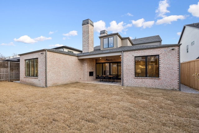 rear view of house with a patio, brick siding, a fenced backyard, and a lawn