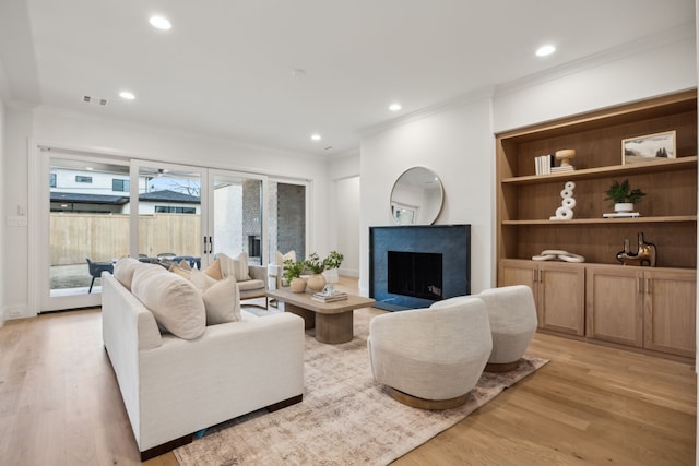 living area with a fireplace, recessed lighting, light wood-style floors, and ornamental molding