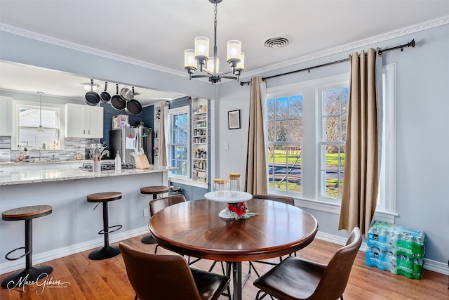 dining space featuring light wood-style flooring, baseboards, and visible vents