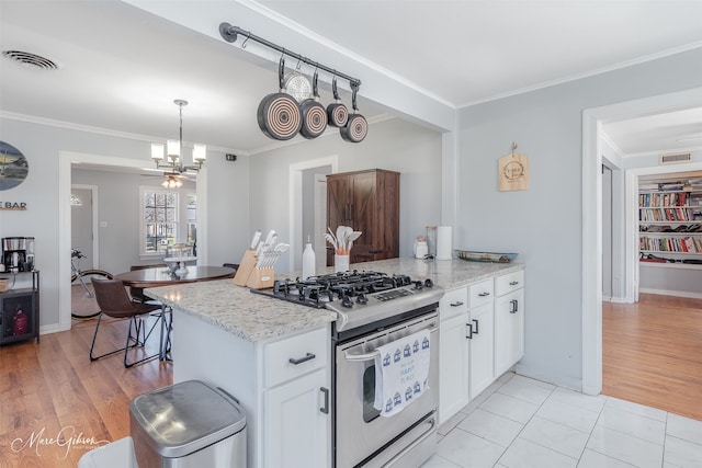 kitchen with visible vents, a peninsula, ornamental molding, white cabinetry, and stainless steel gas stove