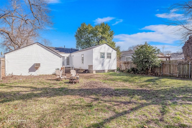 rear view of property featuring a fenced backyard, an outdoor fire pit, and a yard