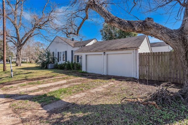 view of property exterior with a lawn, an attached garage, and fence