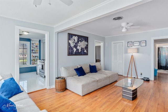 living area with visible vents, crown molding, ceiling fan, and wood finished floors