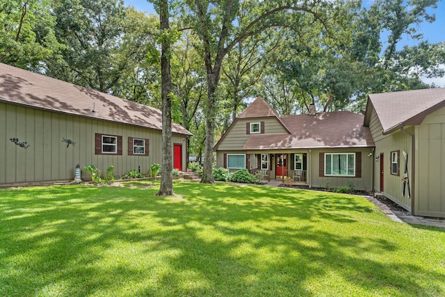 view of front of house with covered porch, a chimney, and a front lawn