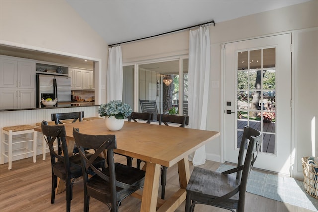 dining area with light wood-style floors and vaulted ceiling