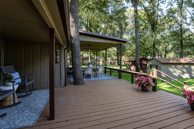 wooden terrace with outdoor dining space, a storage shed, an outdoor structure, and ceiling fan