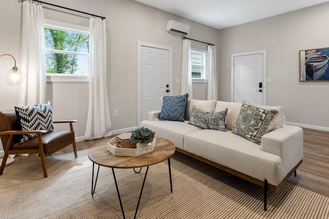 living room featuring an AC wall unit, light wood-style floors, and baseboards