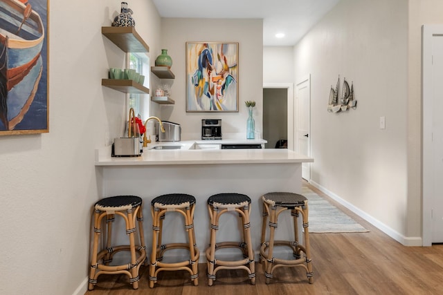 kitchen with open shelves, wood finished floors, baseboards, and light countertops