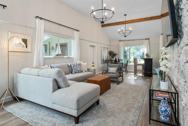 living area featuring lofted ceiling with beams, a notable chandelier, wood finished floors, and baseboards