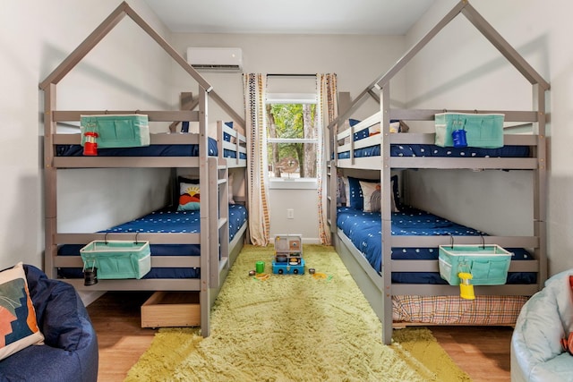 bedroom featuring wood finished floors and a wall mounted AC