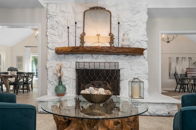 living area featuring lofted ceiling, a stone fireplace, and wood finished floors