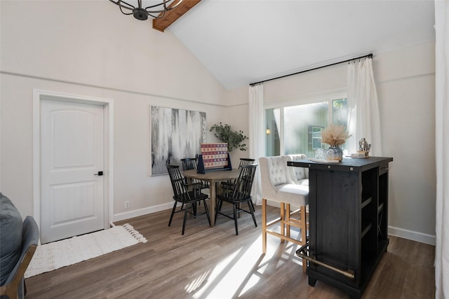 dining area featuring wood finished floors, baseboards, and high vaulted ceiling