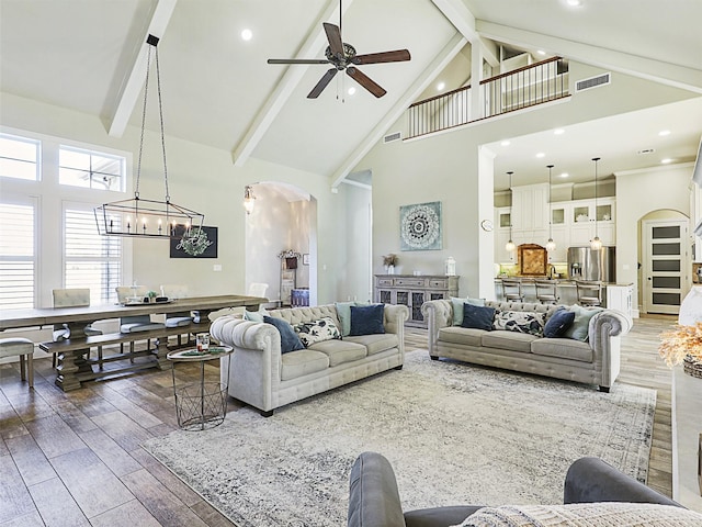 living area featuring arched walkways, high vaulted ceiling, and wood finished floors