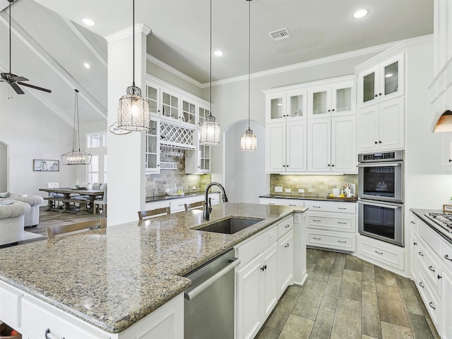 kitchen with visible vents, a sink, open floor plan, stainless steel appliances, and a kitchen island with sink