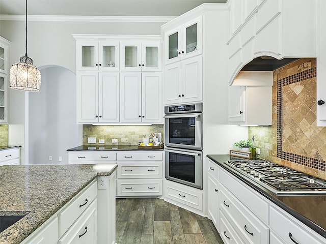 kitchen with dark wood-style floors, premium range hood, dark stone counters, stainless steel appliances, and crown molding