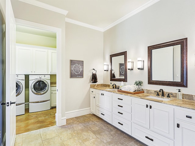 bathroom with a sink, baseboards, crown molding, and washer and clothes dryer