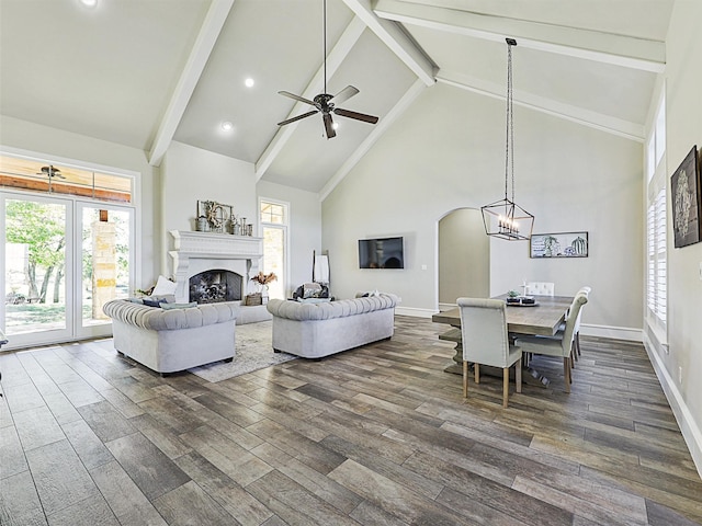 living room featuring plenty of natural light, high vaulted ceiling, a fireplace, and dark wood-style flooring