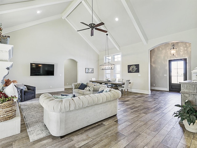 living area featuring arched walkways, high vaulted ceiling, beam ceiling, and wood finished floors