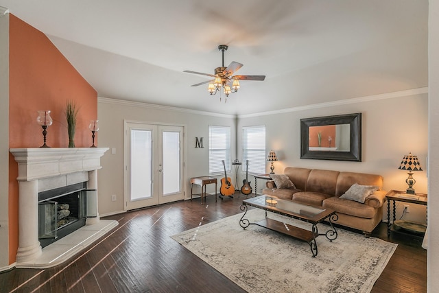 living area with french doors, a fireplace with raised hearth, dark wood-style floors, and crown molding