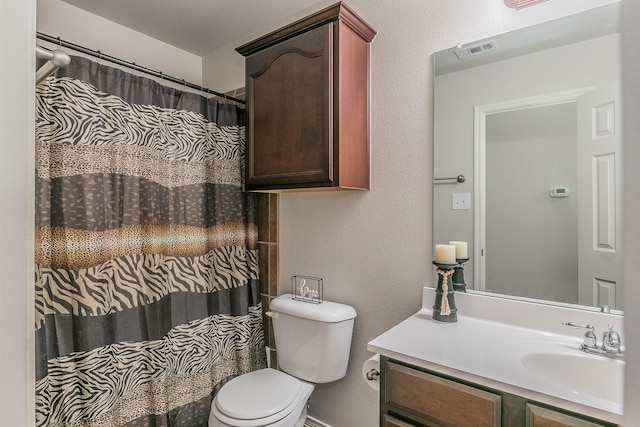 full bathroom with vanity, a shower with curtain, visible vents, toilet, and a textured wall