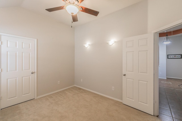 carpeted spare room with vaulted ceiling, baseboards, and ceiling fan