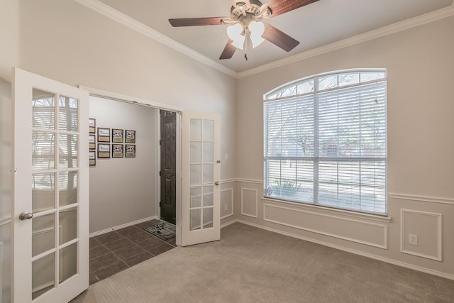 carpeted empty room with crown molding, a decorative wall, french doors, and a wainscoted wall