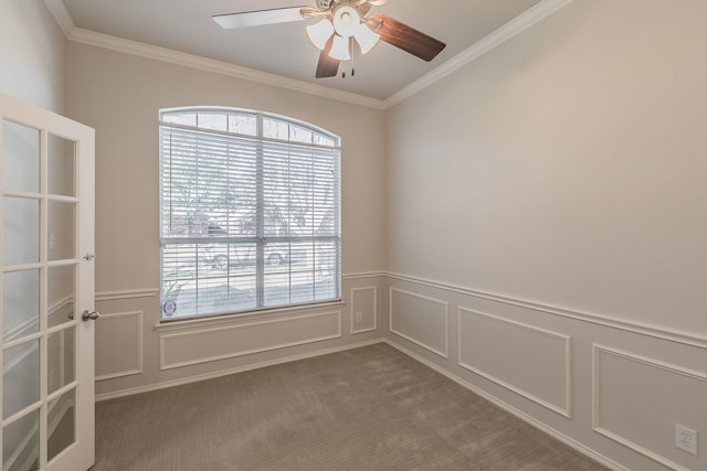 spare room with a ceiling fan, carpet, a wainscoted wall, and ornamental molding