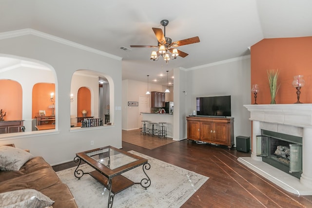 living area featuring dark wood-type flooring, crown molding, lofted ceiling, and a fireplace with raised hearth