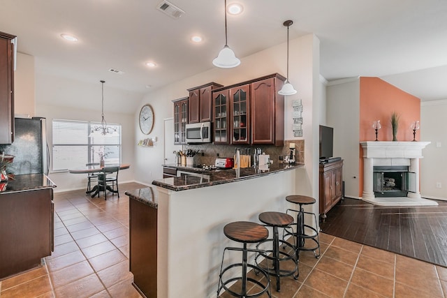 kitchen featuring tile patterned floors, visible vents, backsplash, appliances with stainless steel finishes, and glass insert cabinets