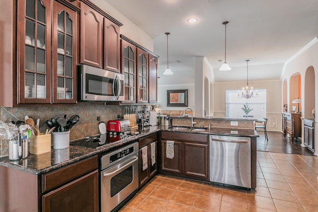 kitchen with backsplash, light tile patterned floors, a peninsula, stainless steel appliances, and a sink