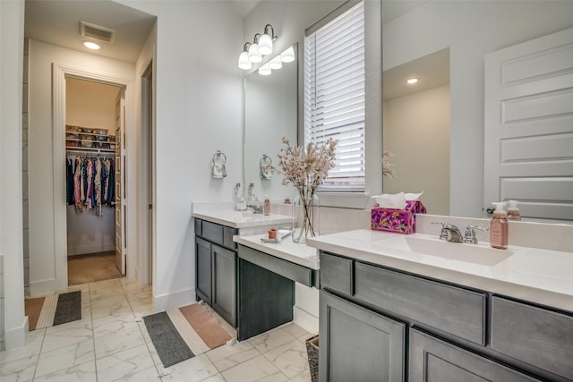 bathroom with visible vents, a walk in closet, baseboards, marble finish floor, and vanity