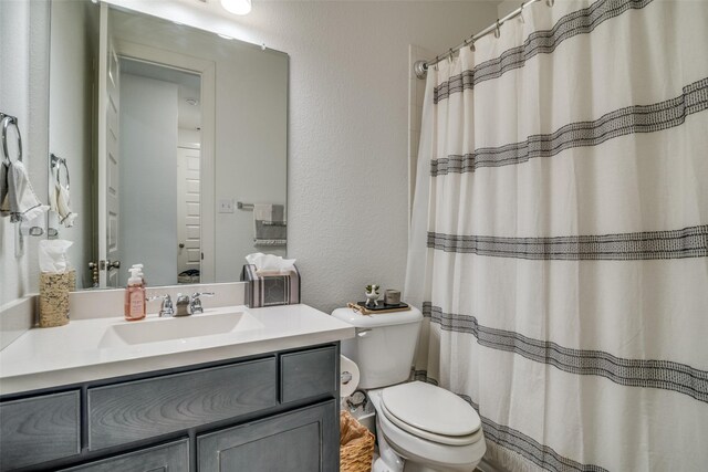 full bathroom featuring a shower with curtain, toilet, vanity, and a textured wall